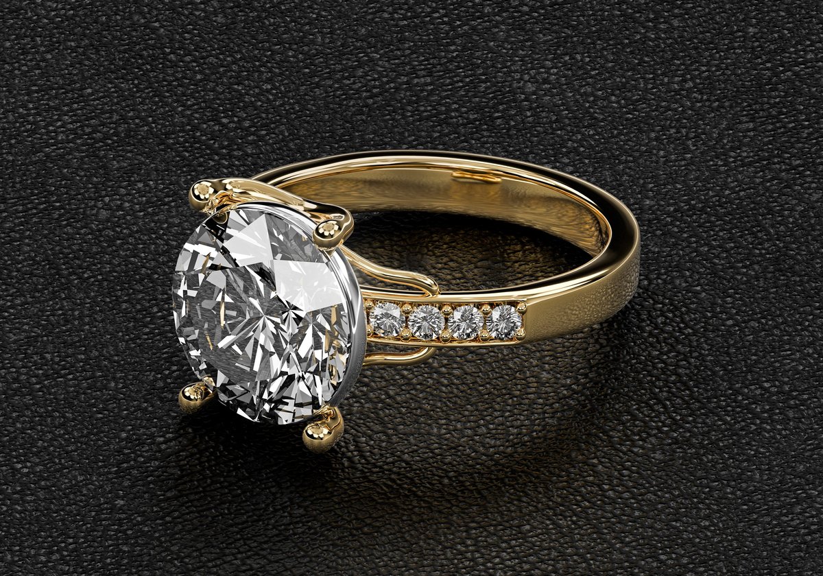 Gold and diamond engagement ring on a dark leather surface